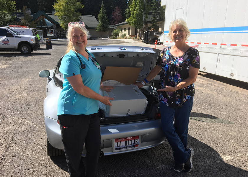 Two women stand in front of open car trunk