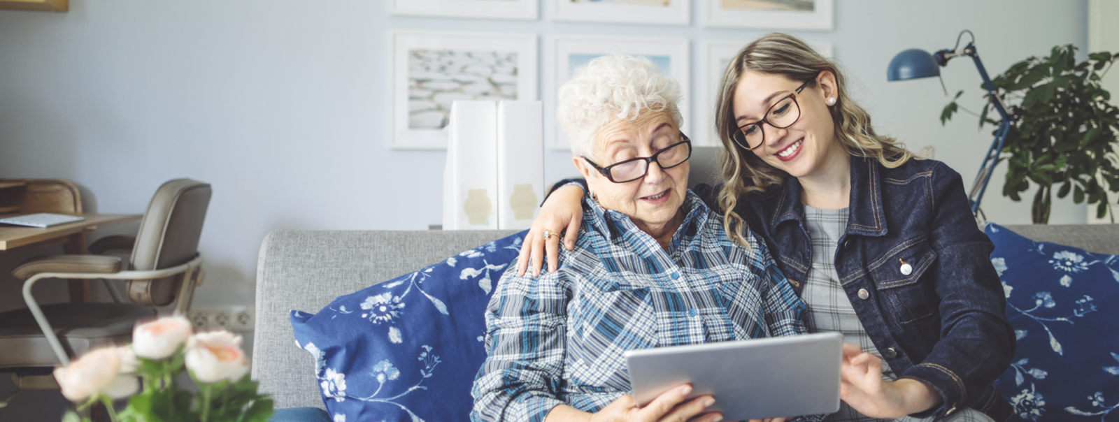 Two women on a sofa using a tablet computer.