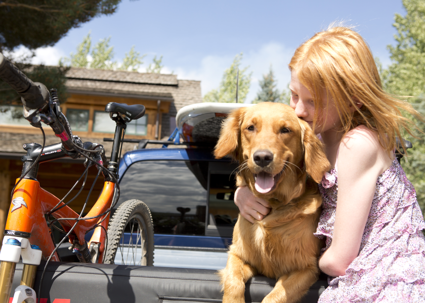 Girl hugs dog outside.